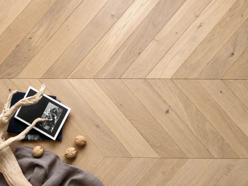 Light oak herringbone wood flooring with visible natural grain and warm neutral tones.